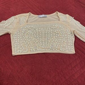 Long-sleeved blouse, ría stones and different types of pearls. From Blue B.